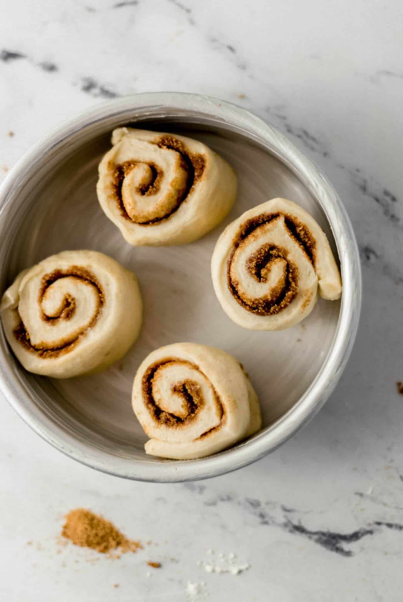 unbaked cinnamon rolls in buttered pan before rising 