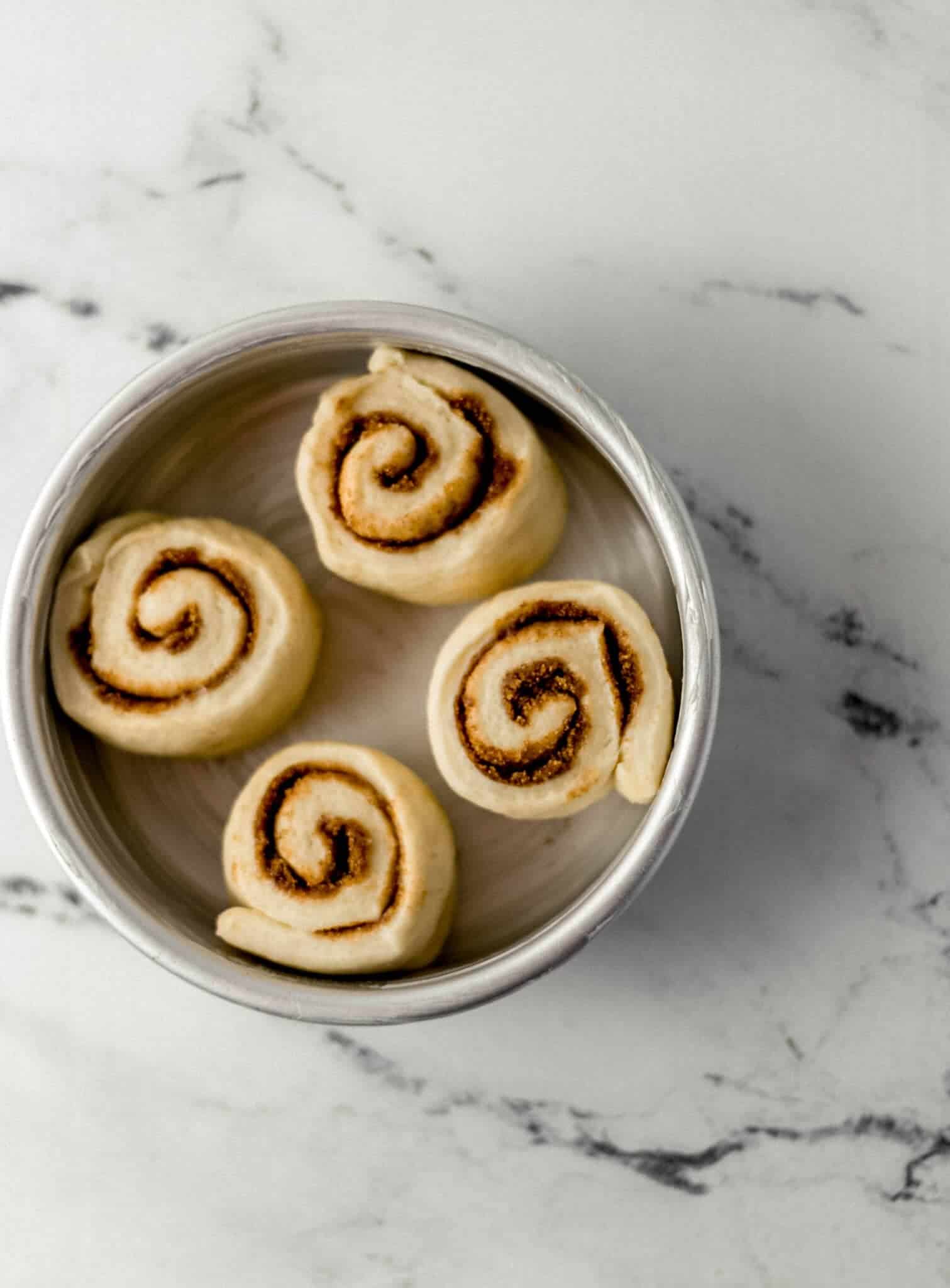 unbaked cinnamon rolls in buttered baking pan after rising 