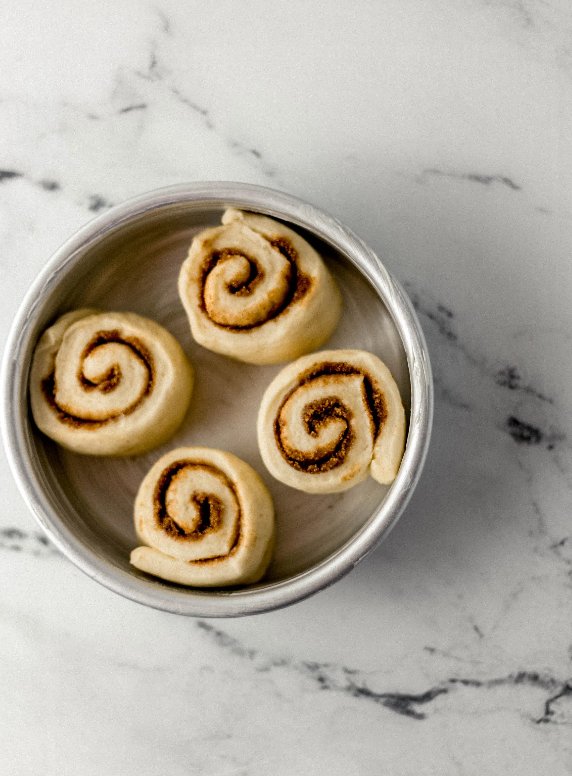 unbaked cinnamon rolls in buttered baking pan after rising 