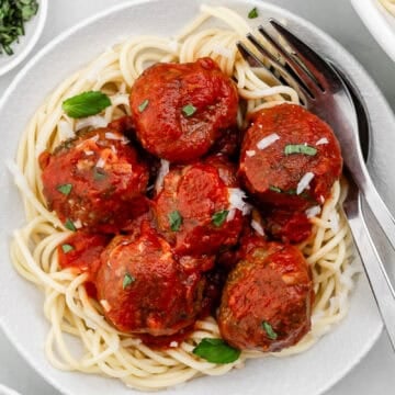 Overhead view of plate of spaghetti with fork and spoon in it.