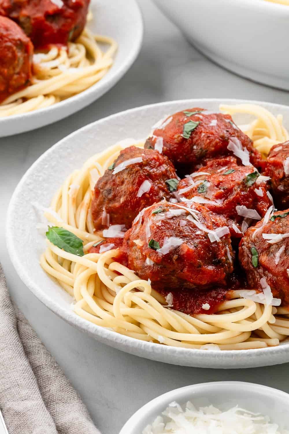 Close up side view of plate of spaghetti with another in the background.