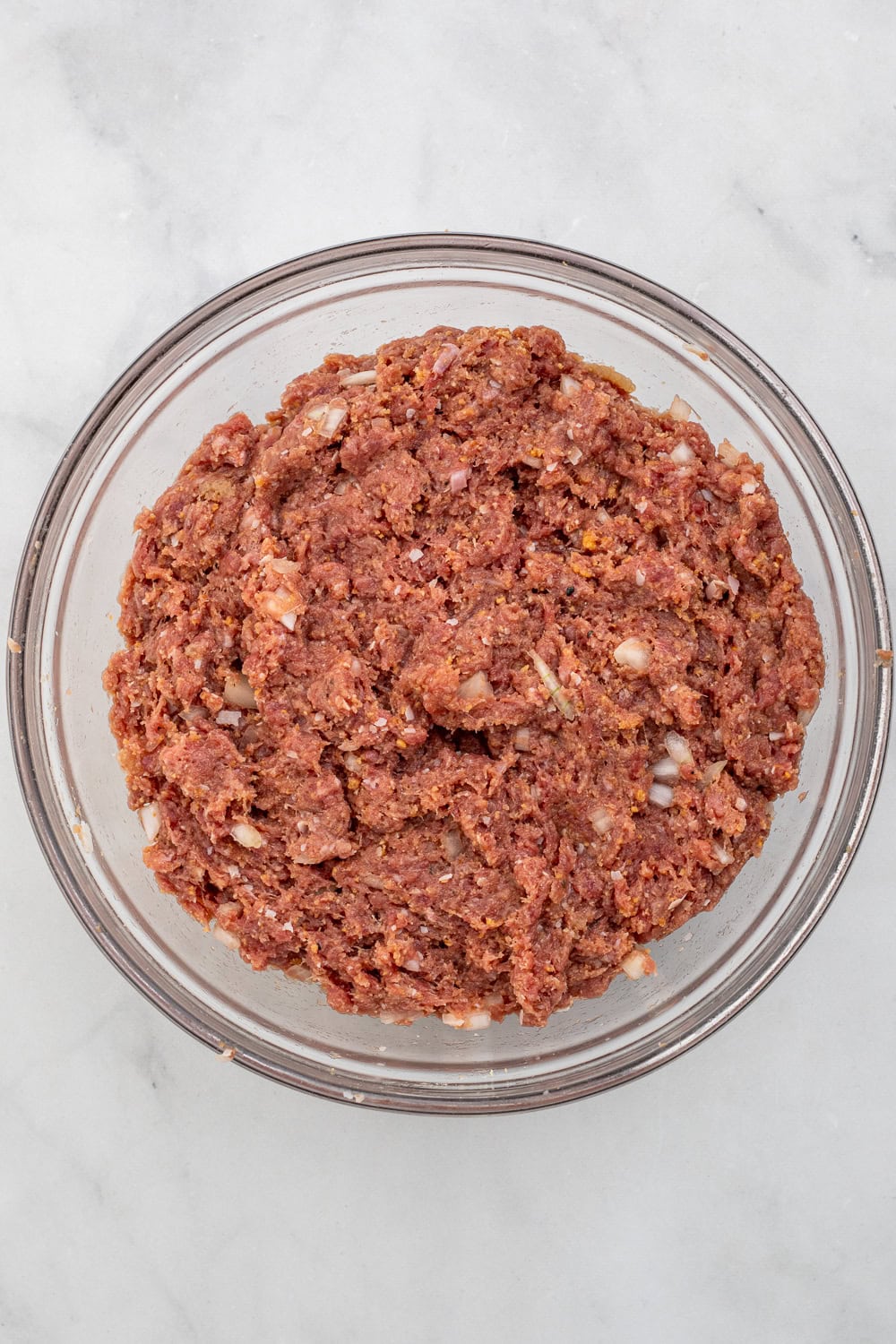 Meatball mixture in glass mixing bowl.