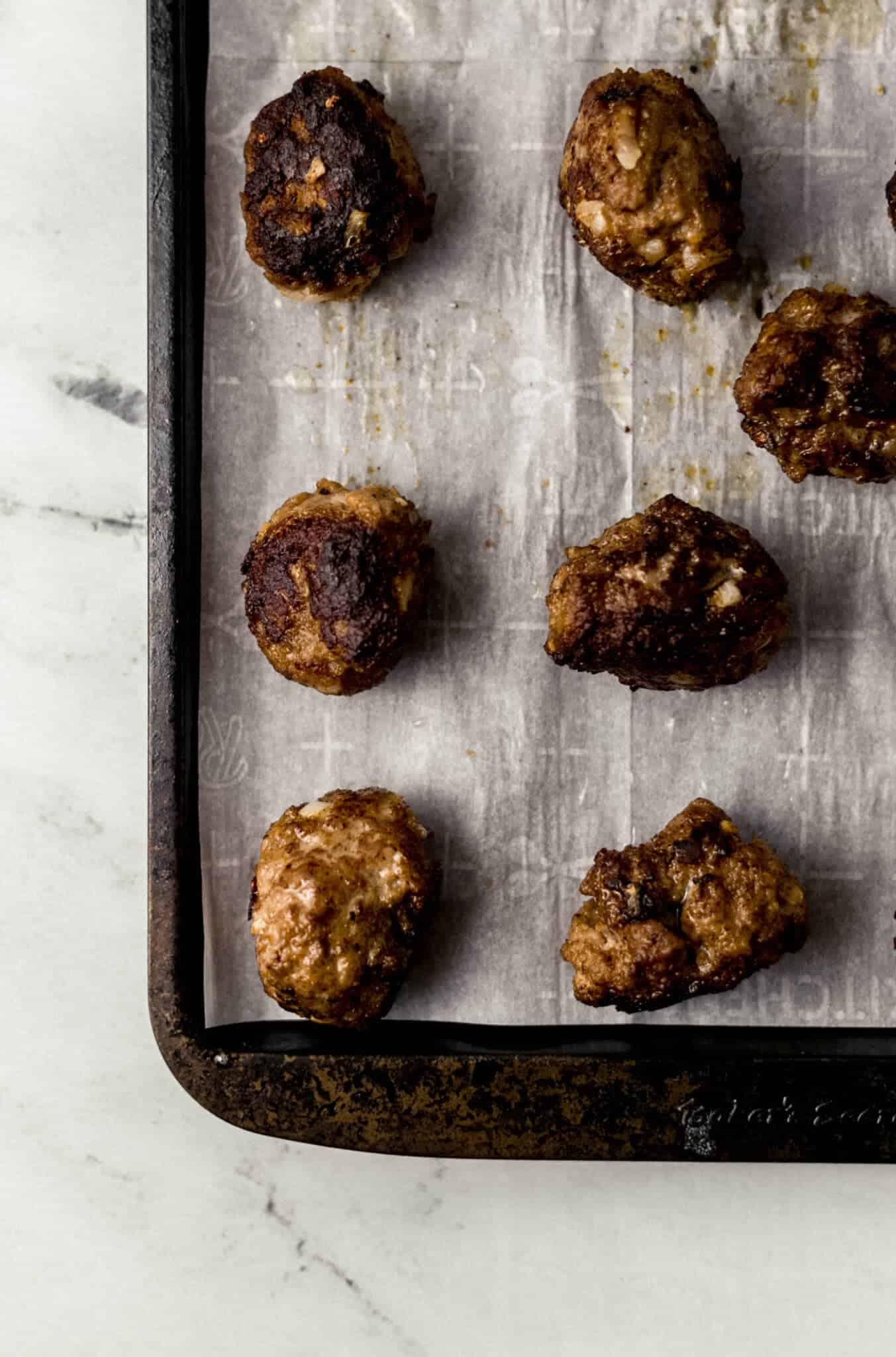 cooked meatballs on parchment lined baking sheet 