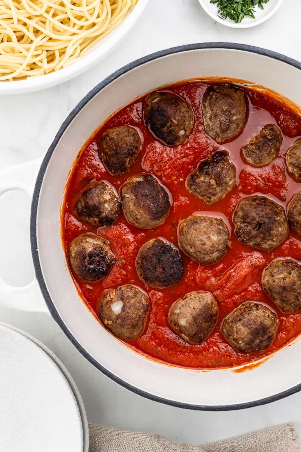 Meatballs added to sauce in large white dutch oven.