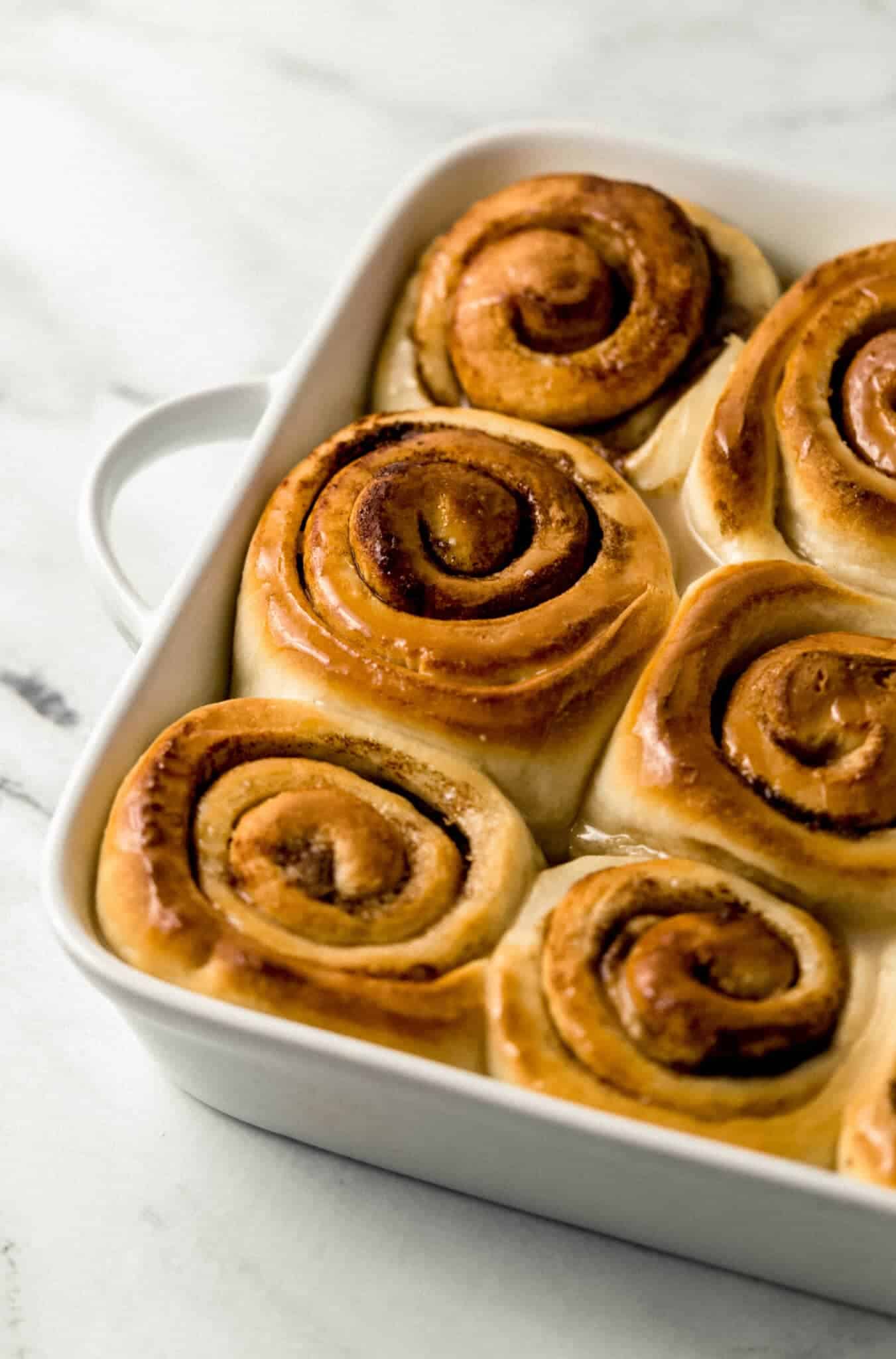 finished cinnamon rolls topped with glaze in baking dish