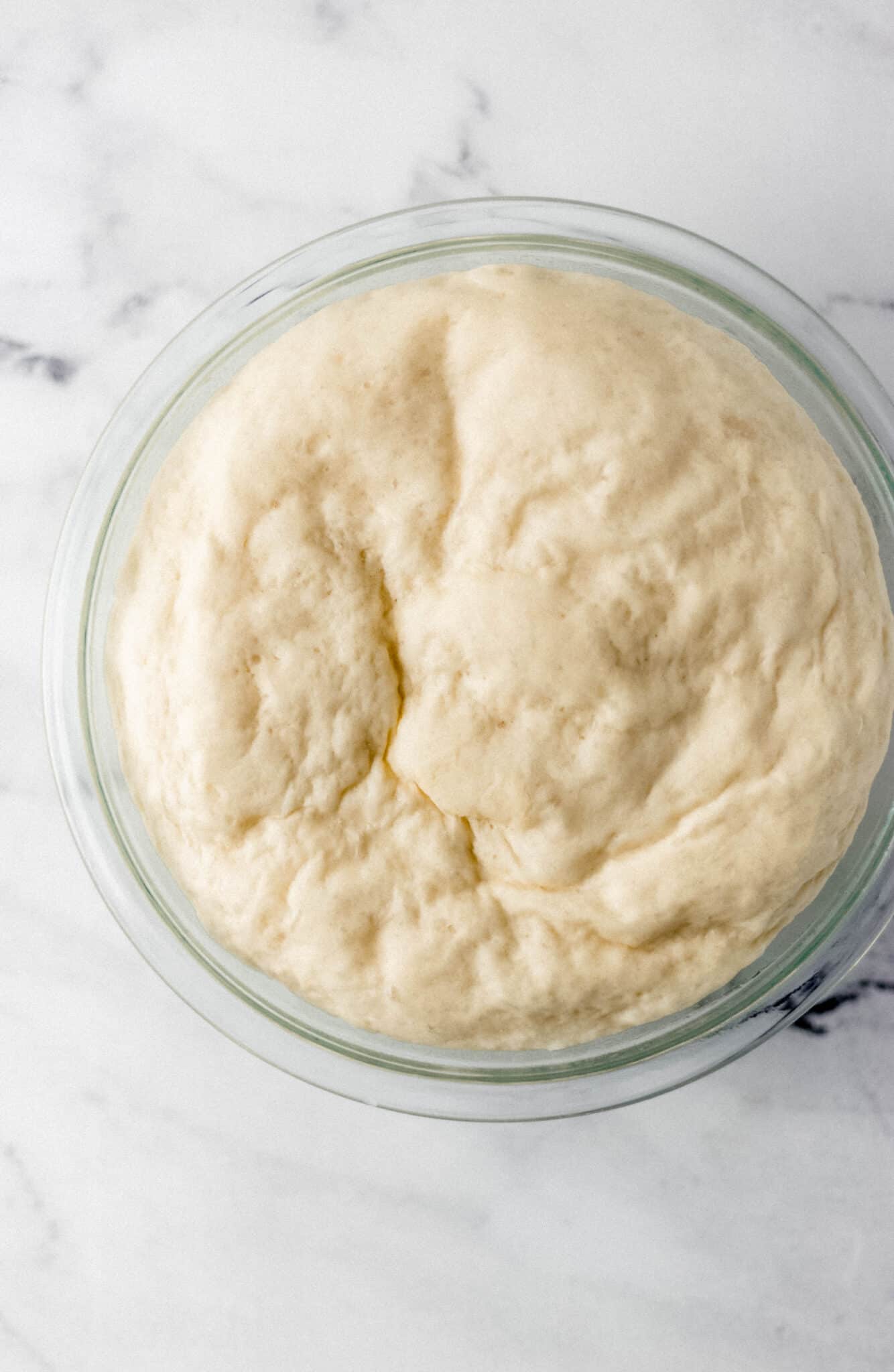 dough that has doubled in size after resting for an hour in a glass bowl