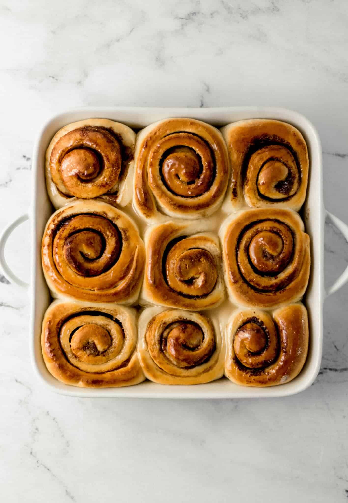 overhead view of finished vegan cinnamon rolls in a white square baking dish