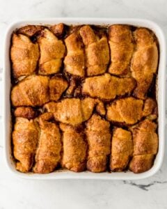 Overhead view of baked apple dumplings in white baking dish.