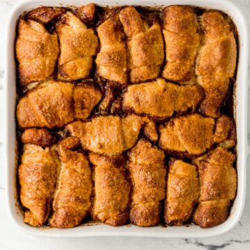 Overhead view of baked apple dumplings in white baking dish.