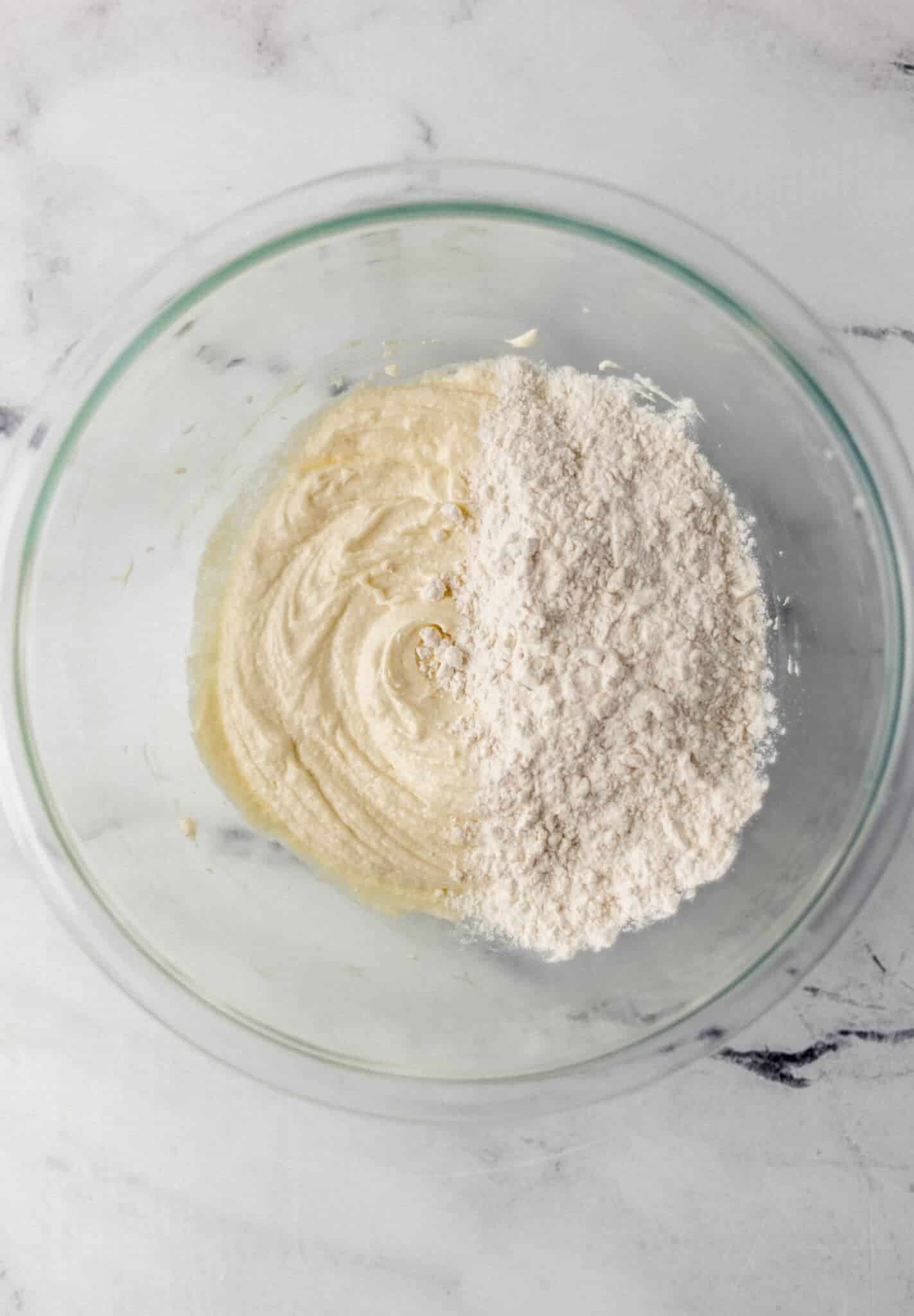 flour and baking powder added to ingredients in glass mixing bowl