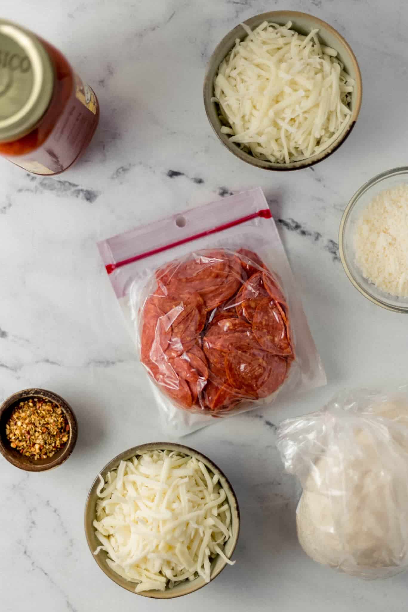 overhead view of ingredients needed to make pepperoni bread in separate bowls and containers