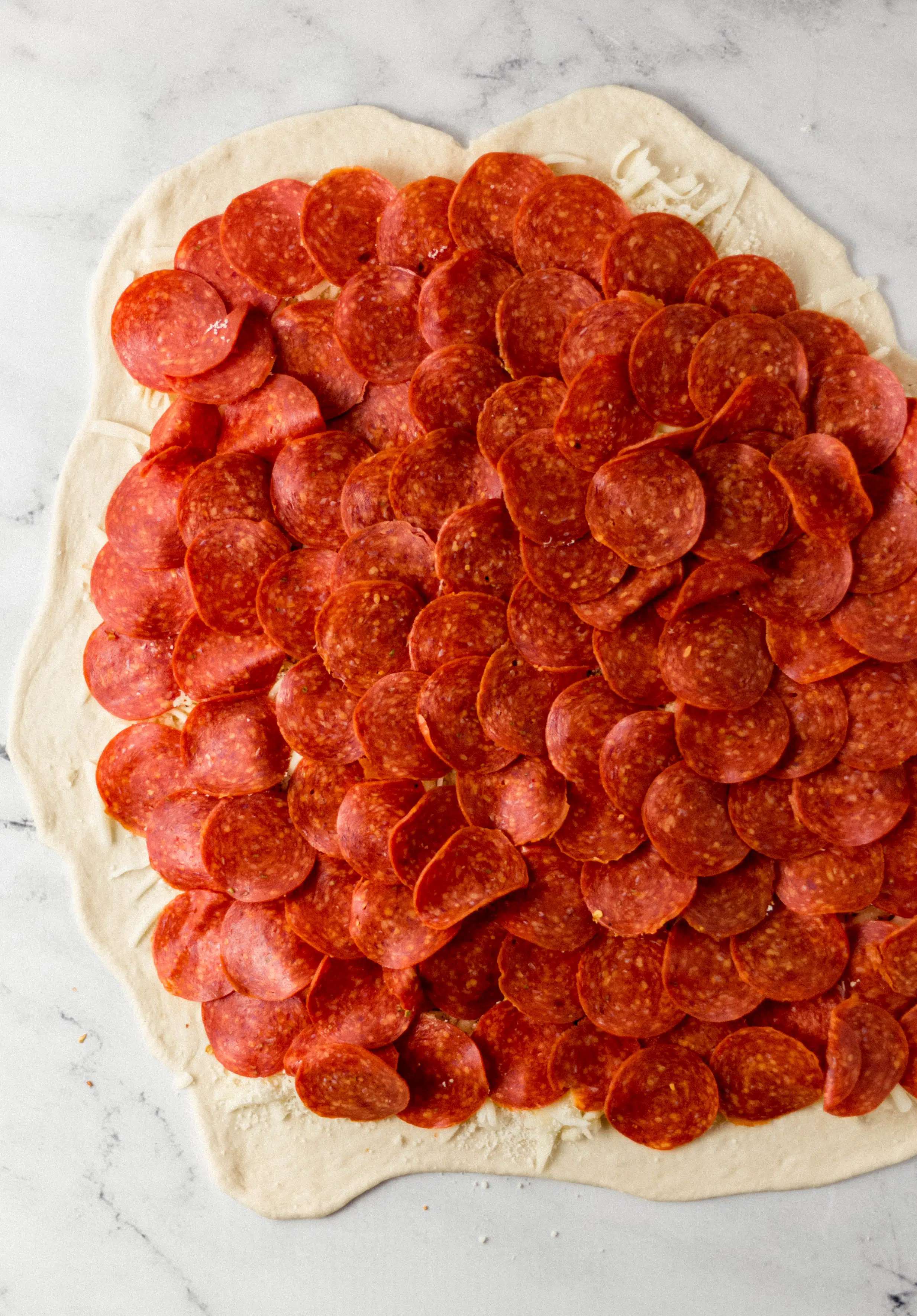 pizza dough topped with pepperoni slices