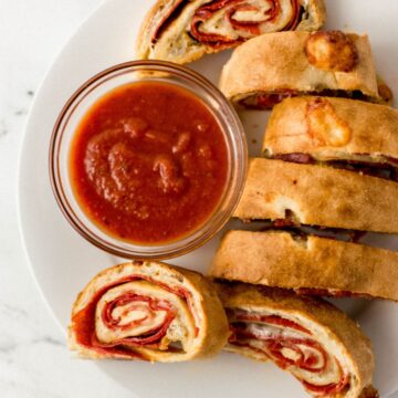 Overhead view of sliced bread on white plate with a small glass bowl of sauce.
