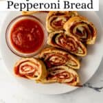 Overhead view of pepperoni bread on white plate with sauce on pin with text overlay.