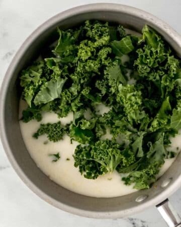 Kale added to saucepan with other soup ingredients.