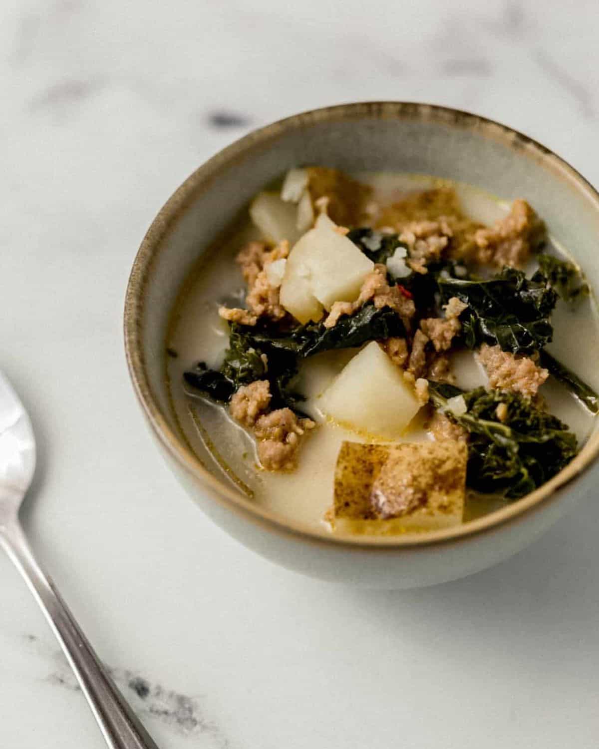 Close up view of bowl of soup by a spoon.