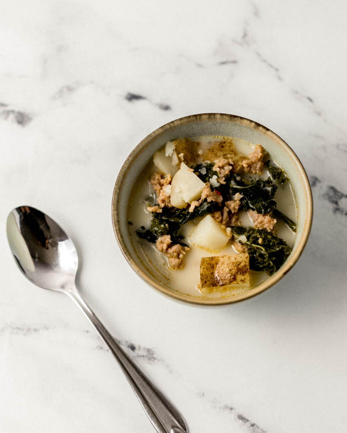 Close up view of bowl of soup by a spoon.