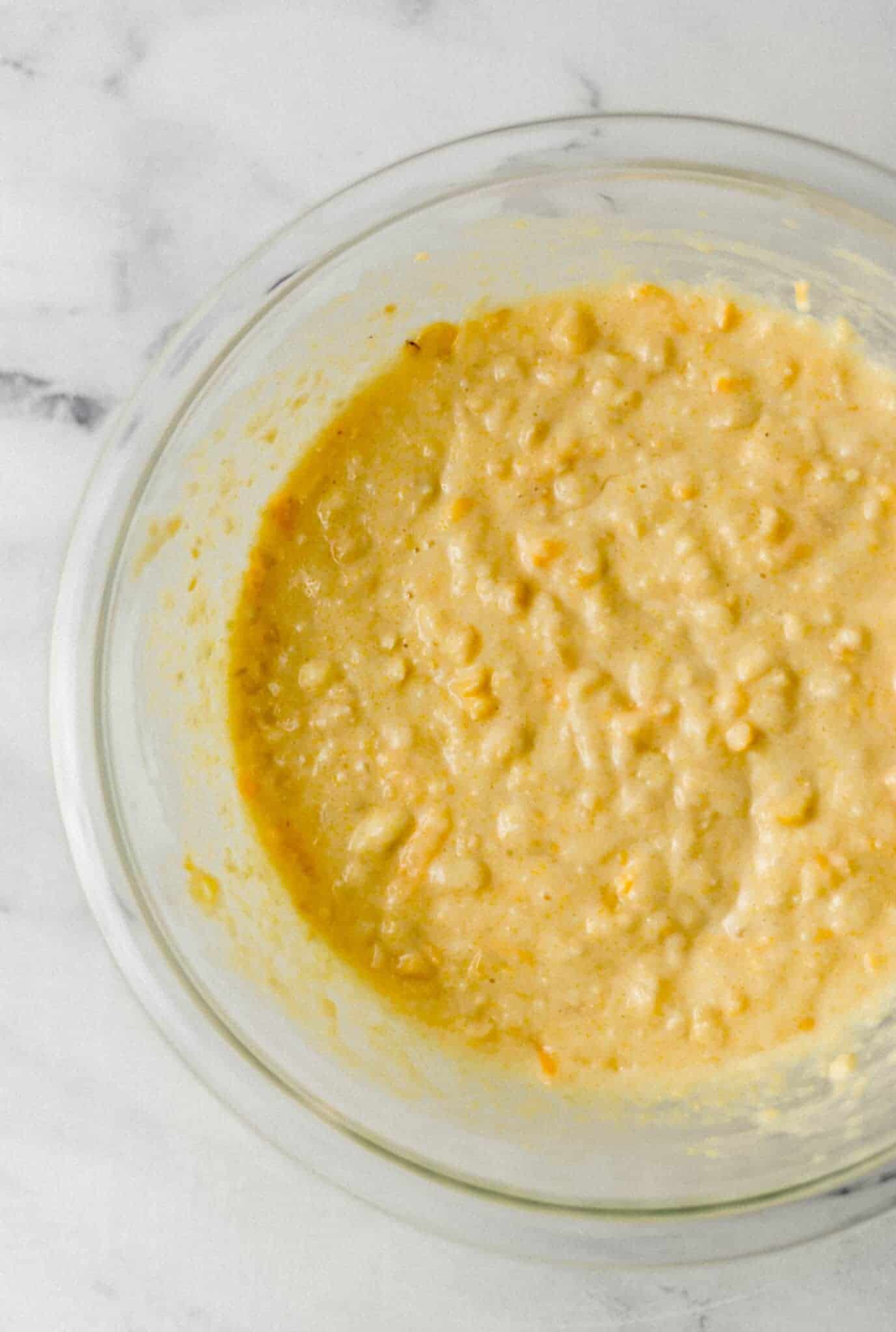 ingredients to make cornbread mixed together in glass mixing bowl