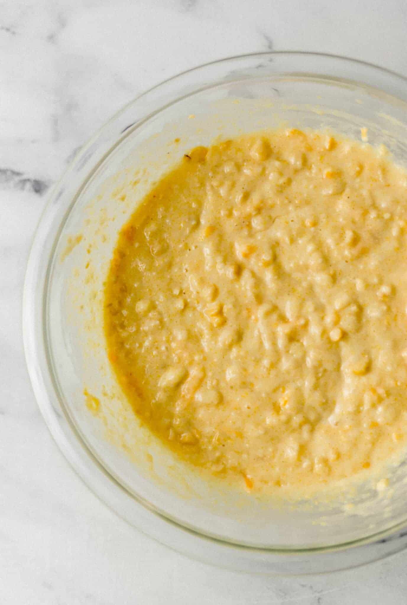 ingredients to make cornbread mixed together in glass mixing bowl 