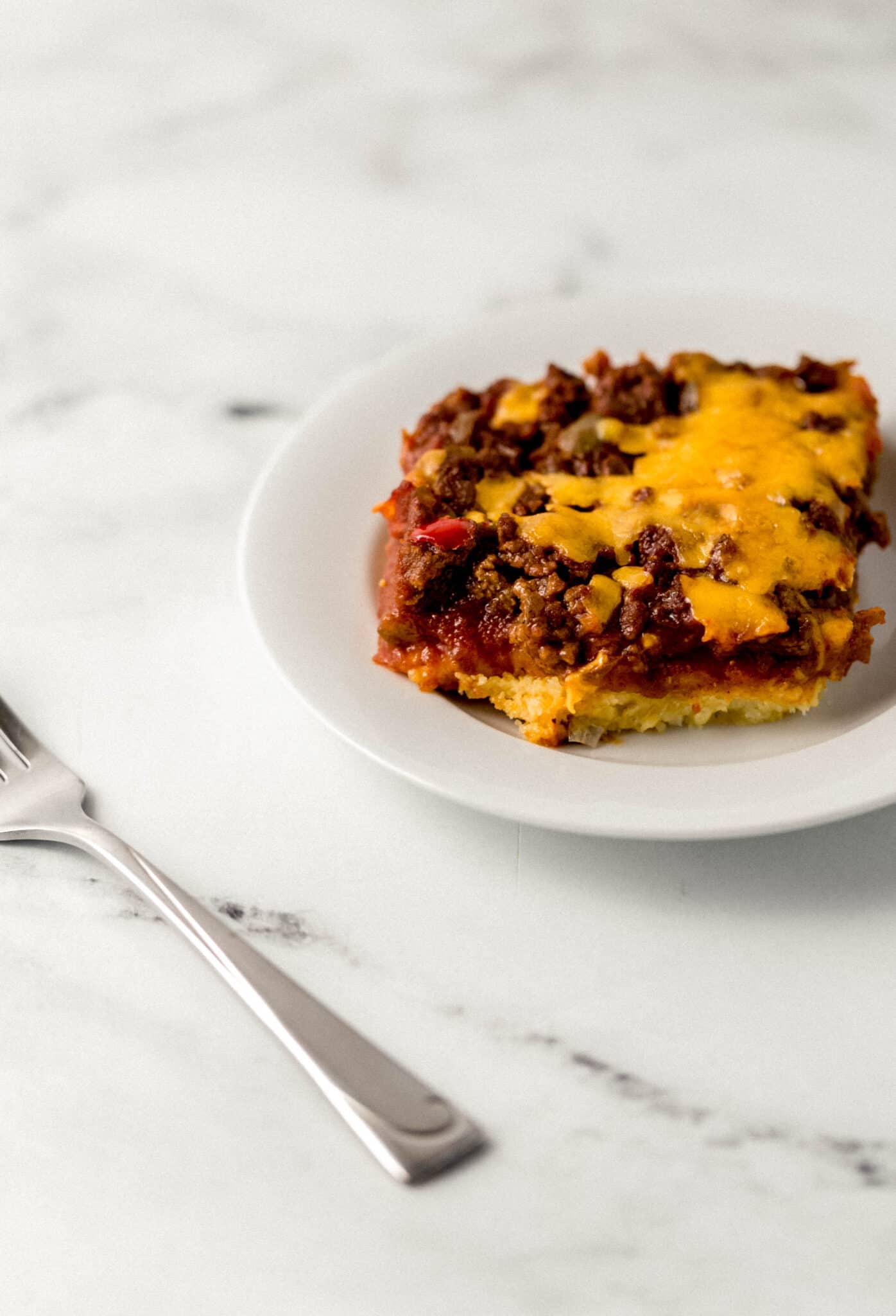 single serving of casserole on small white plate beside a fork