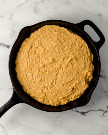 Cornbread batter added to cast iron skillet.