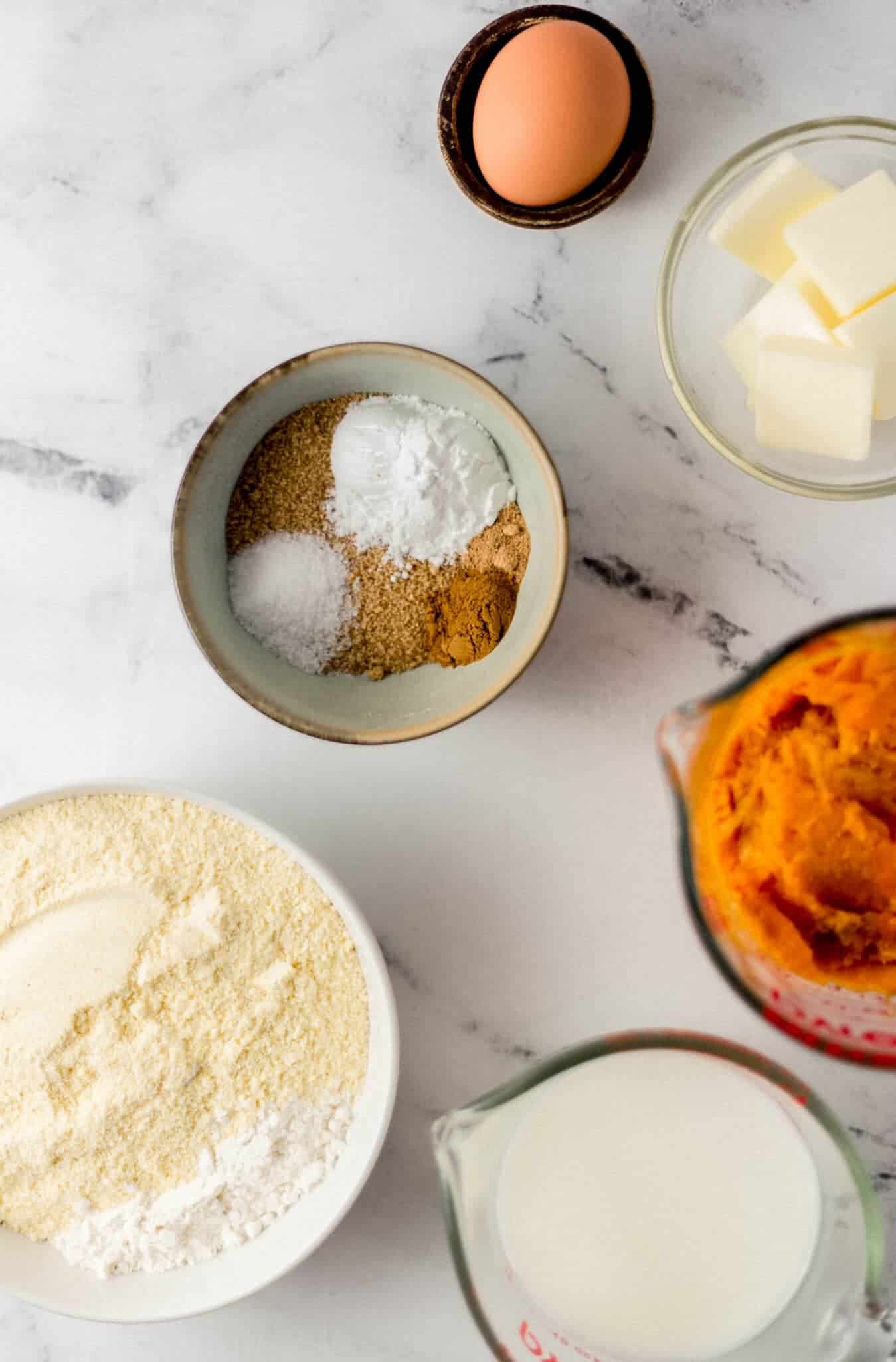 ingredients needed to make cornbread in separate bowls and glass measuring cups