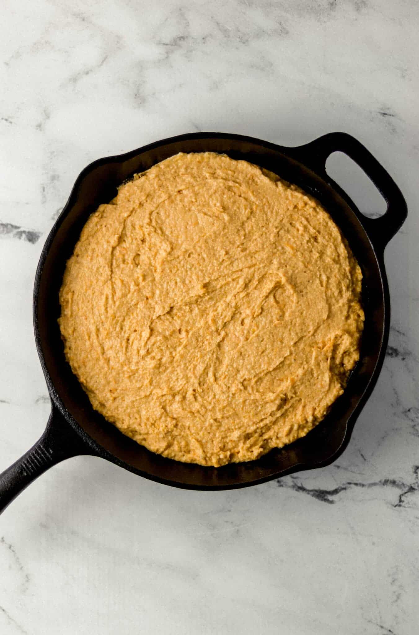 cornbread mixture added to cast iron skillet 