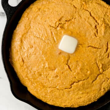 finished sweet potato cornbread in cast iron skillet topped with butter
