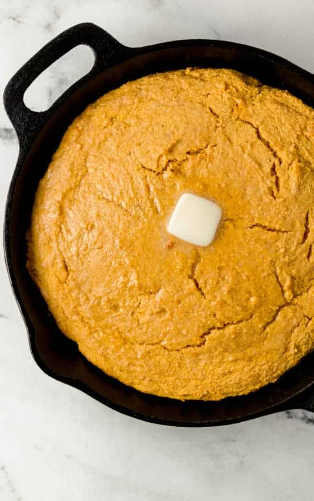 finished sweet potato cornbread in cast iron skillet topped with butter