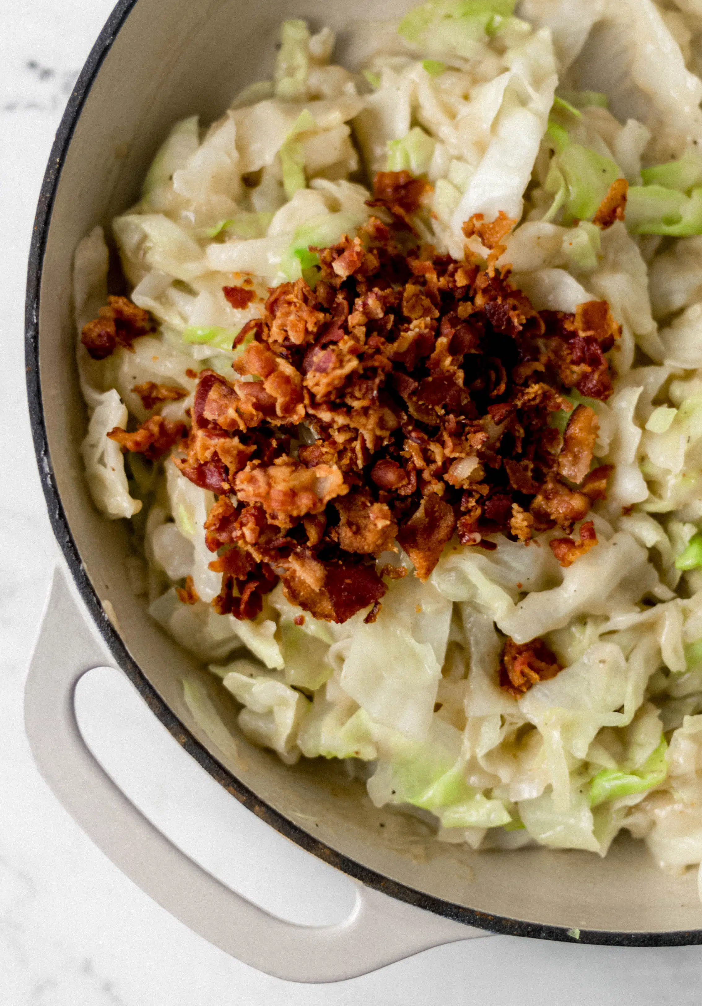 chopped bacon placed on top of cabbage in pan