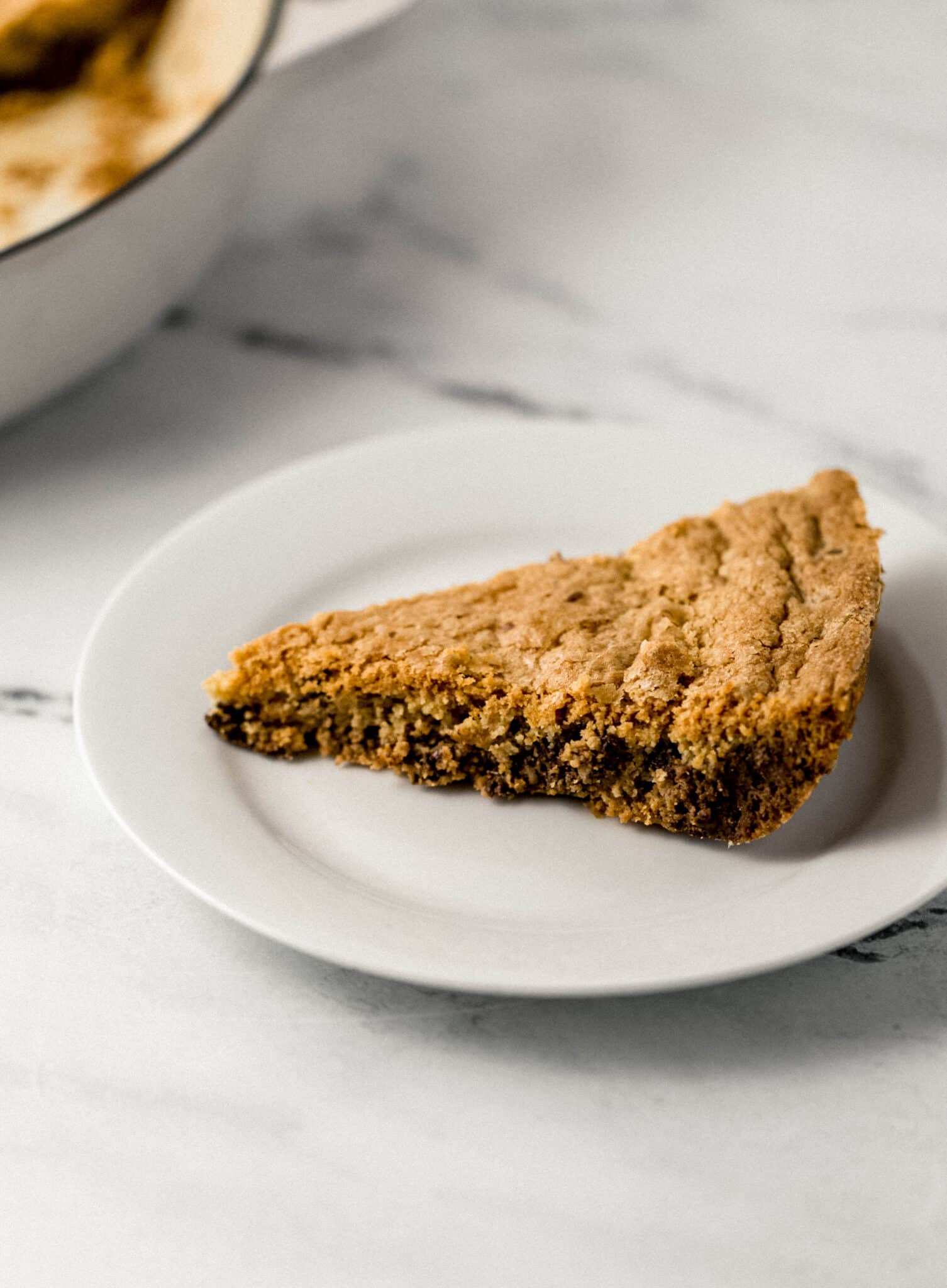 close up side view of a slice of cookie on small white plate 