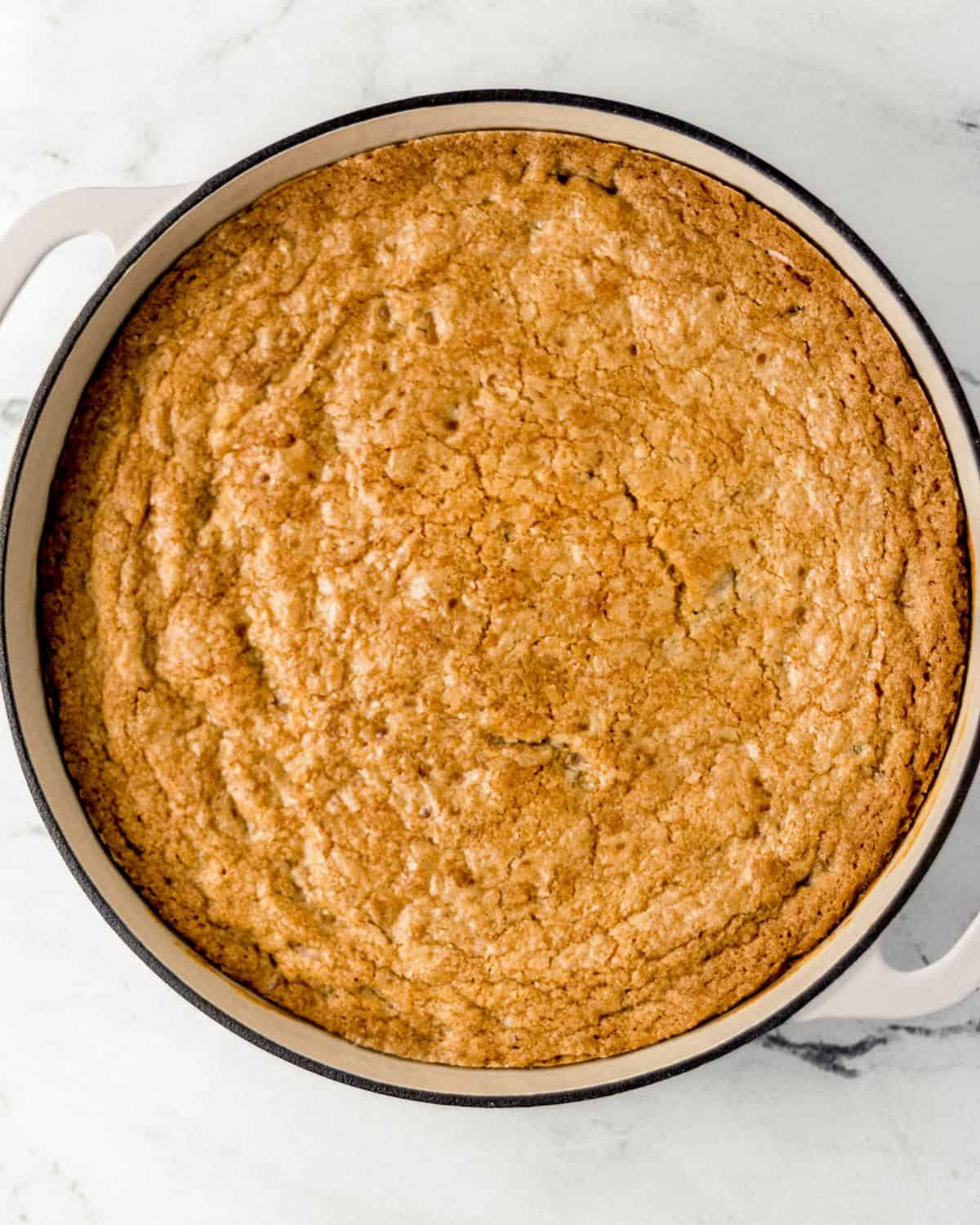 Overhead view of finished cookie in white cast iron braiser pan.