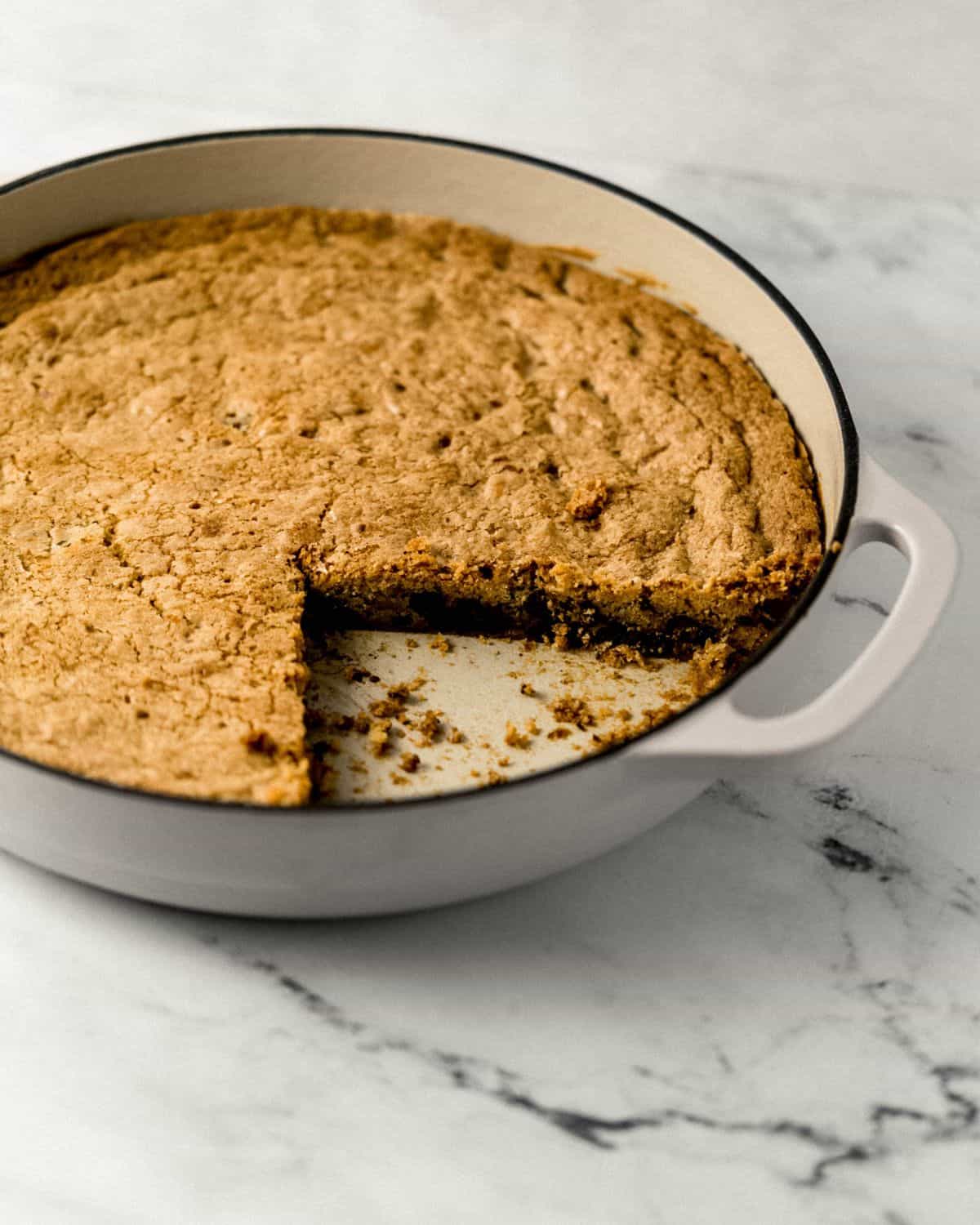 Close up front view of cookie in skillet with some taken out of it.
