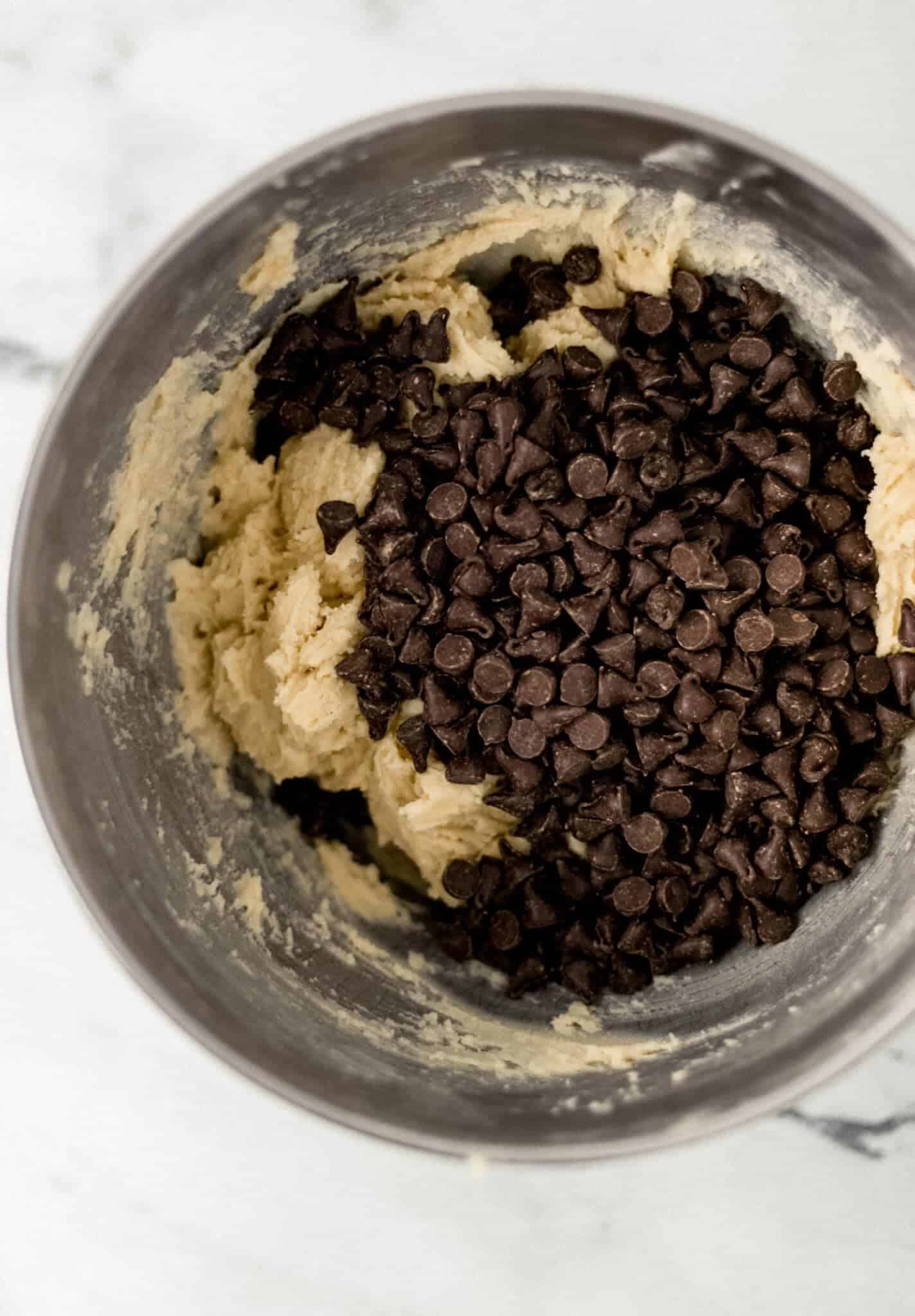 chocolate chips added to cookie mixture in mixing bowl 