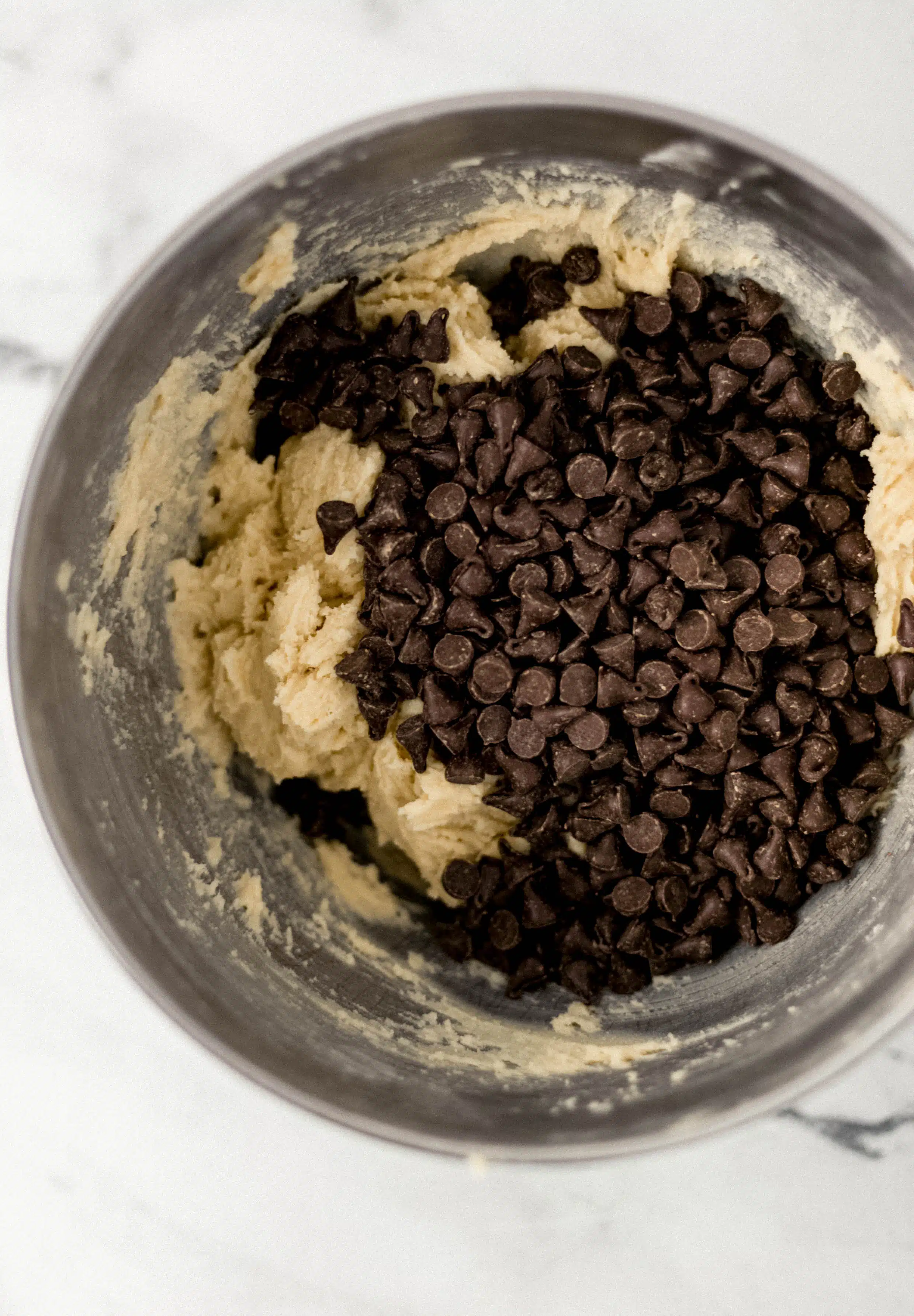 chocolate chips added to cookie mixture in mixing bowl 