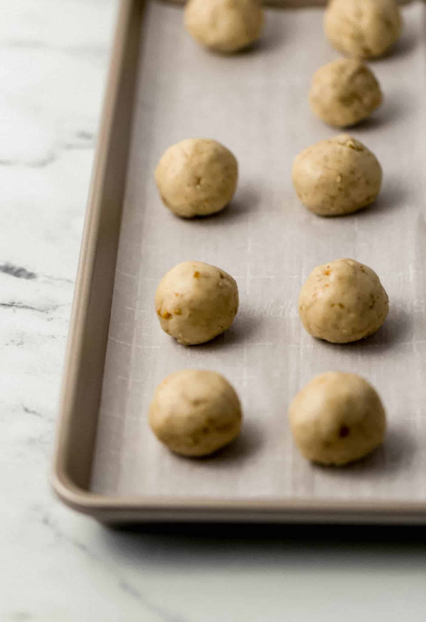 cookie dough balls on parchment lined baking sheet before baking 