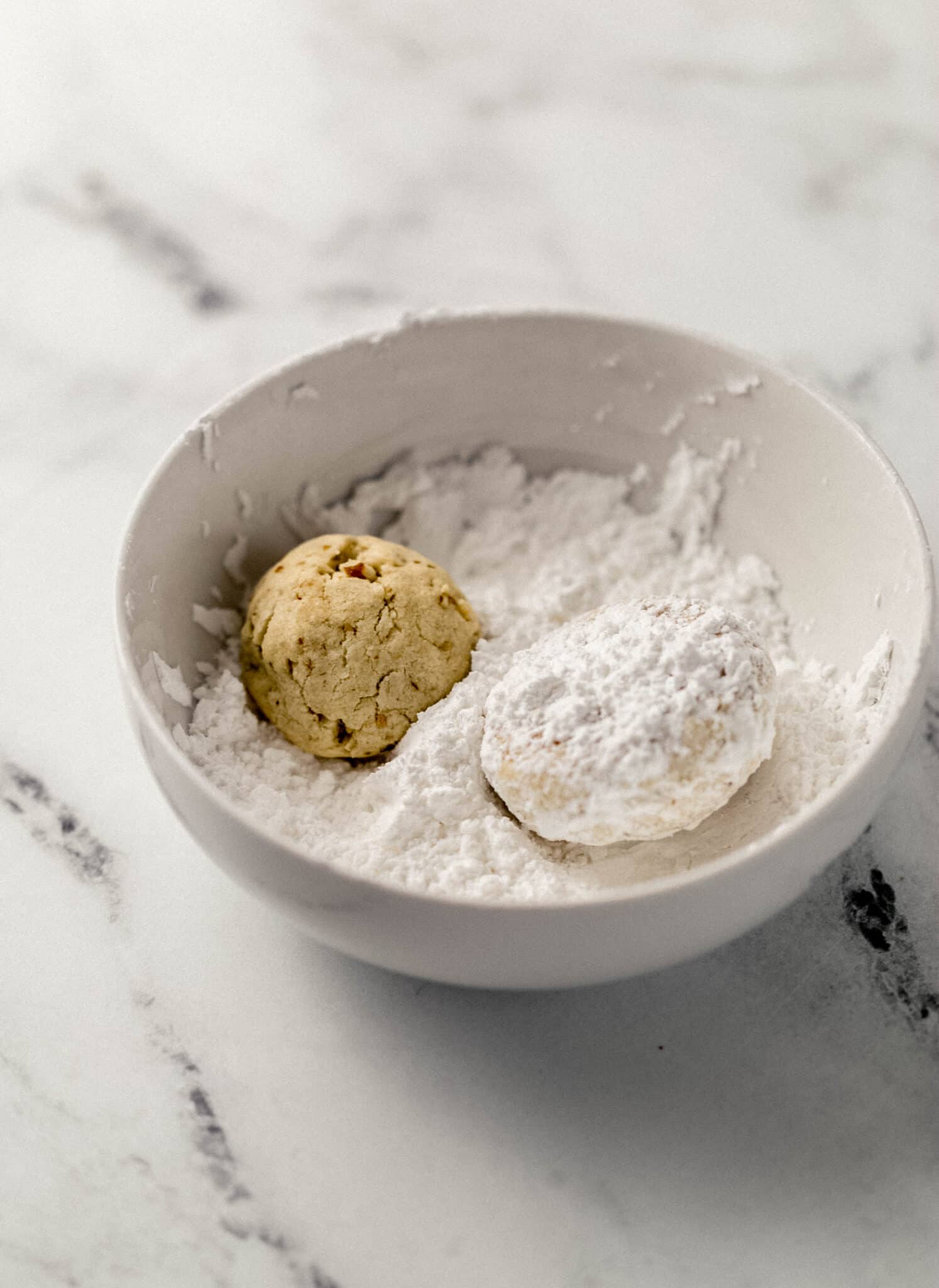 two baked cookies in a white bowl with powdered sugar 