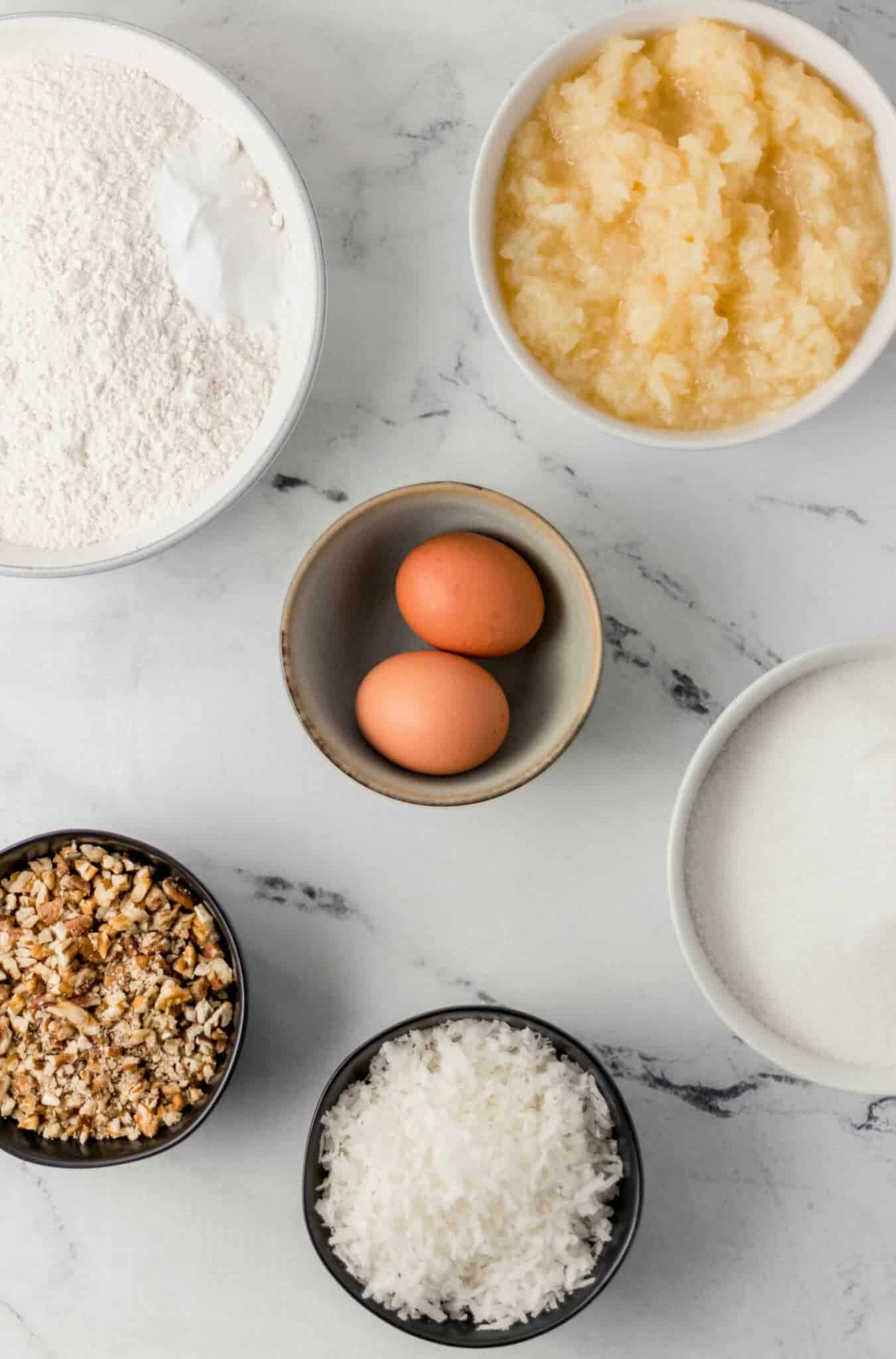 ingredients needed to make cake in separate bowls on marble surface