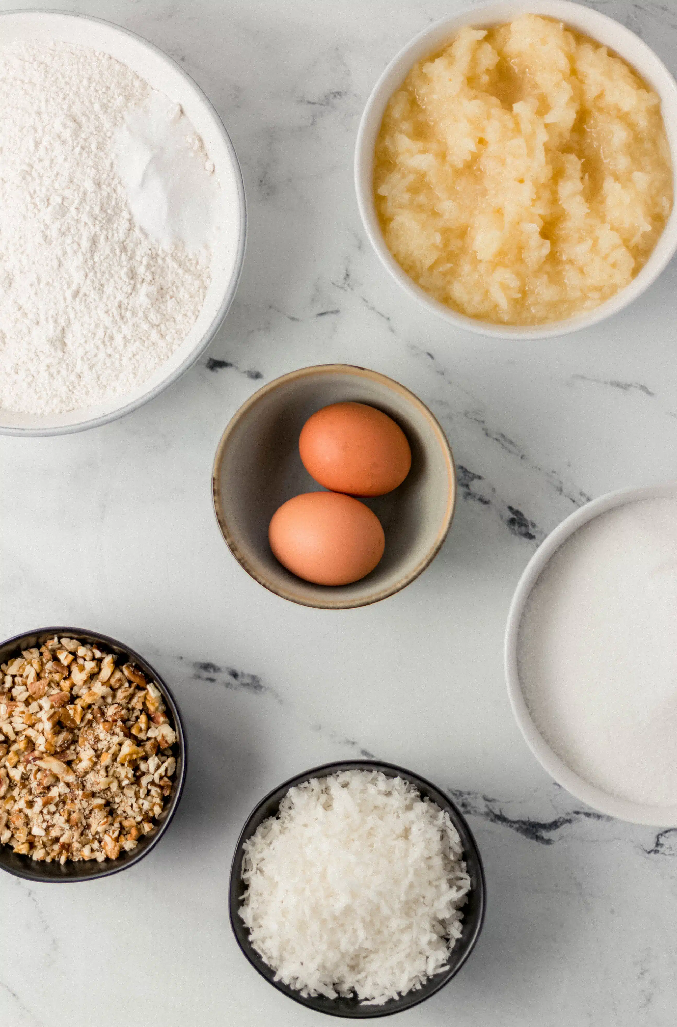 ingredients needed to make cake in separate bowls on marble surface