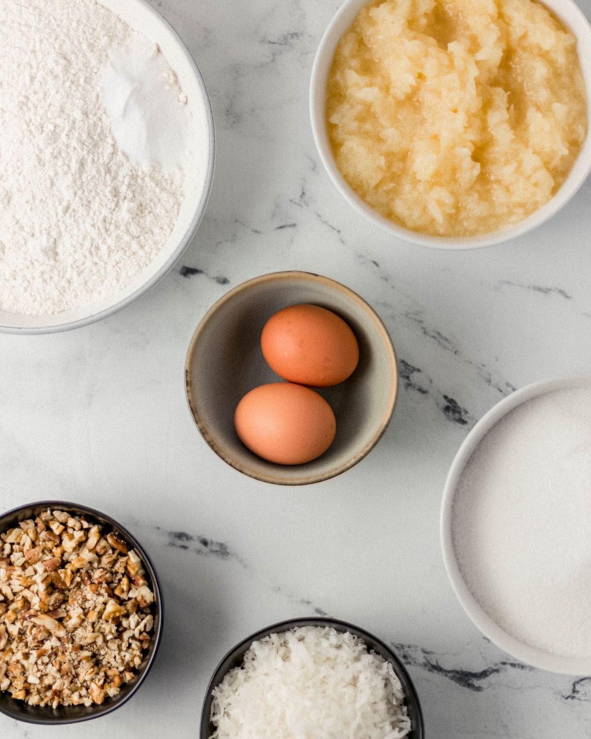 Overhead view of ingredients needed to make cake in separate bowls. 