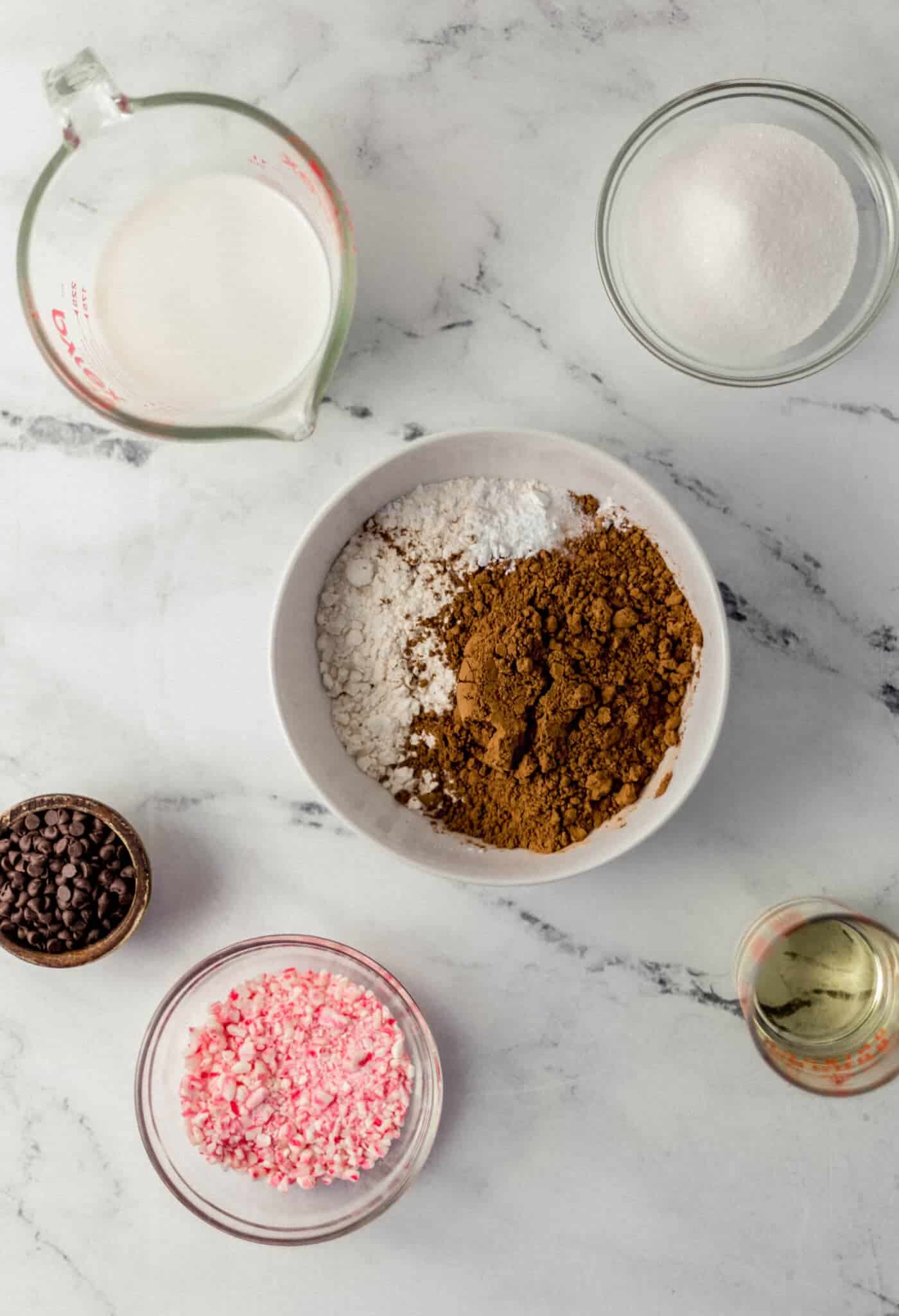 ingredients needed to make mug cakes in separate bowls on marble surface 