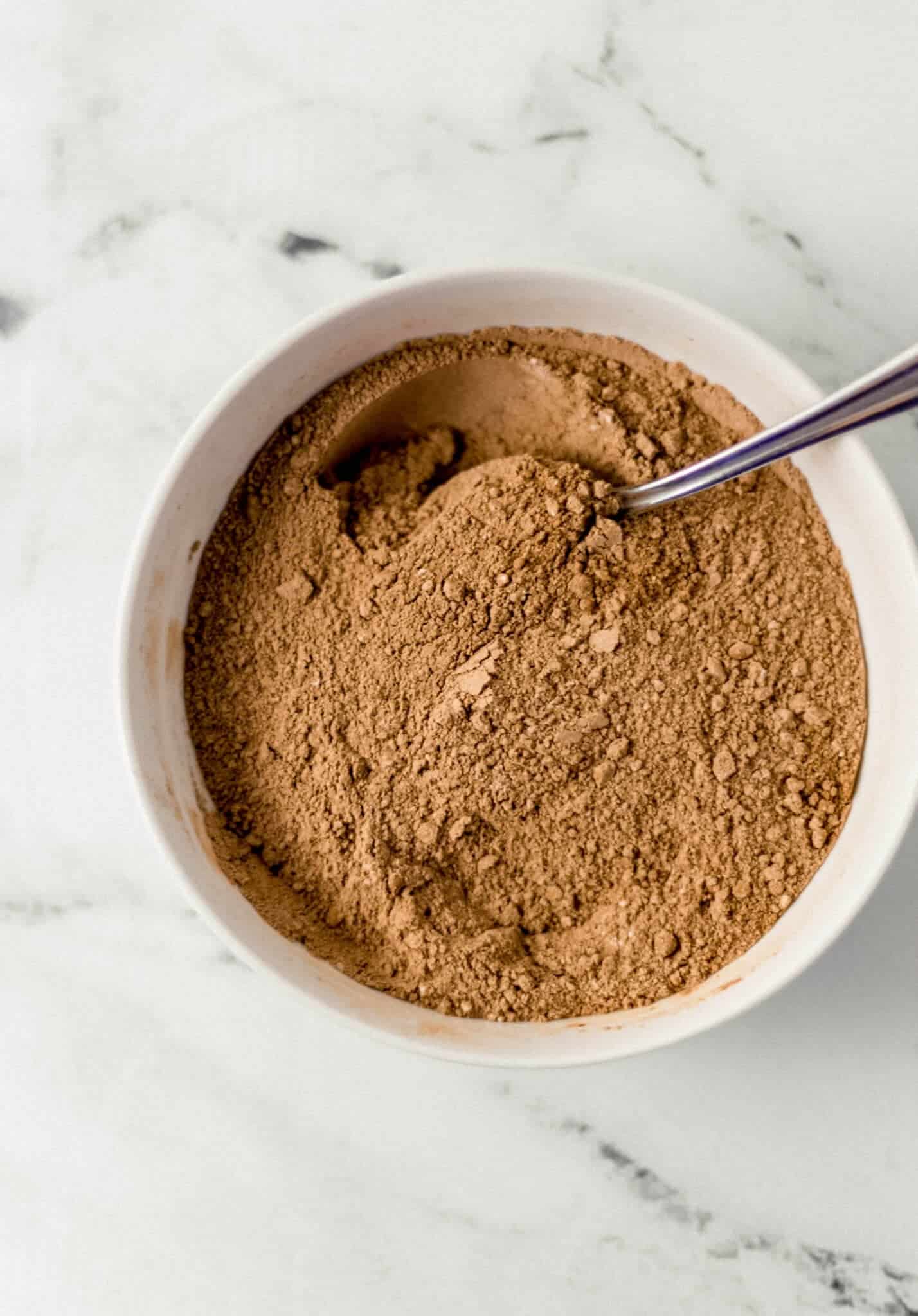 dry ingredients combined in white bowl with spoon 