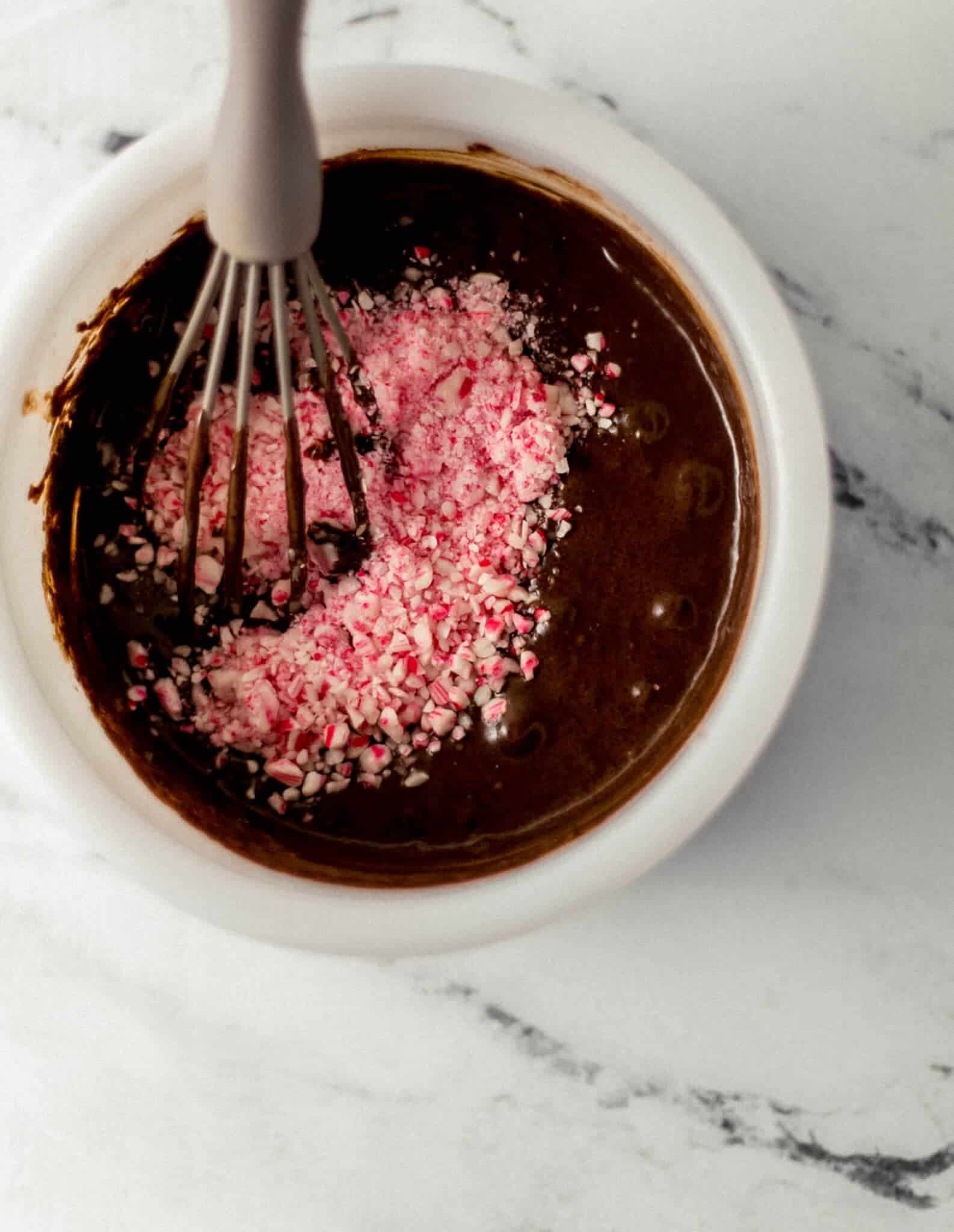 peppermint pieces added to the rest of the cake ingredients in a white mixing bowl with whisk