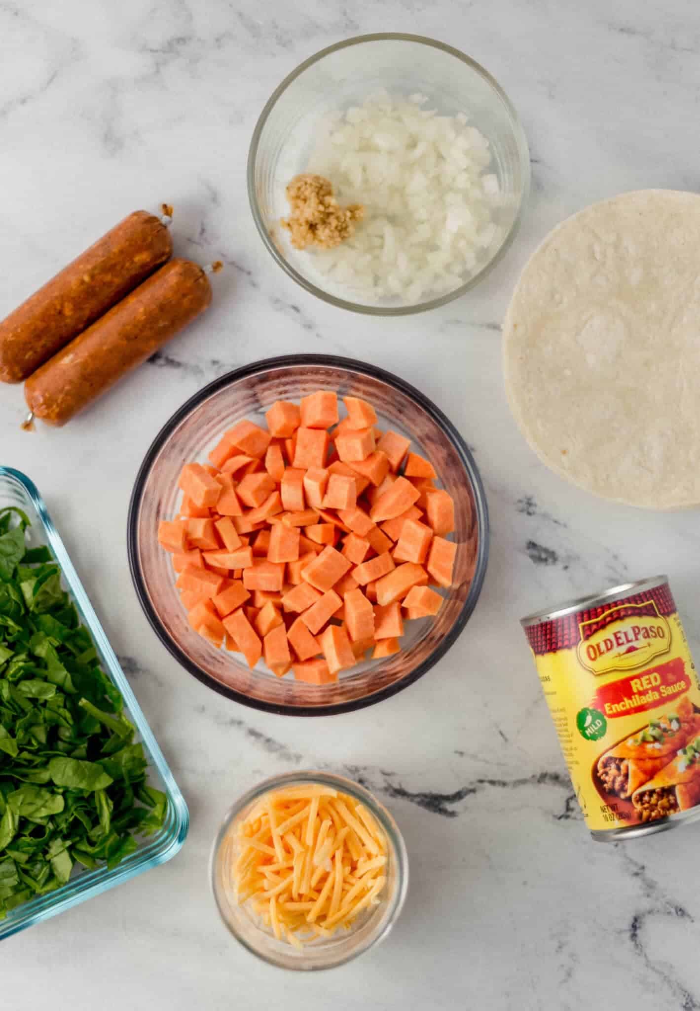 overhead view of ingredients needed to make enchiladas in separate bowls and containers 