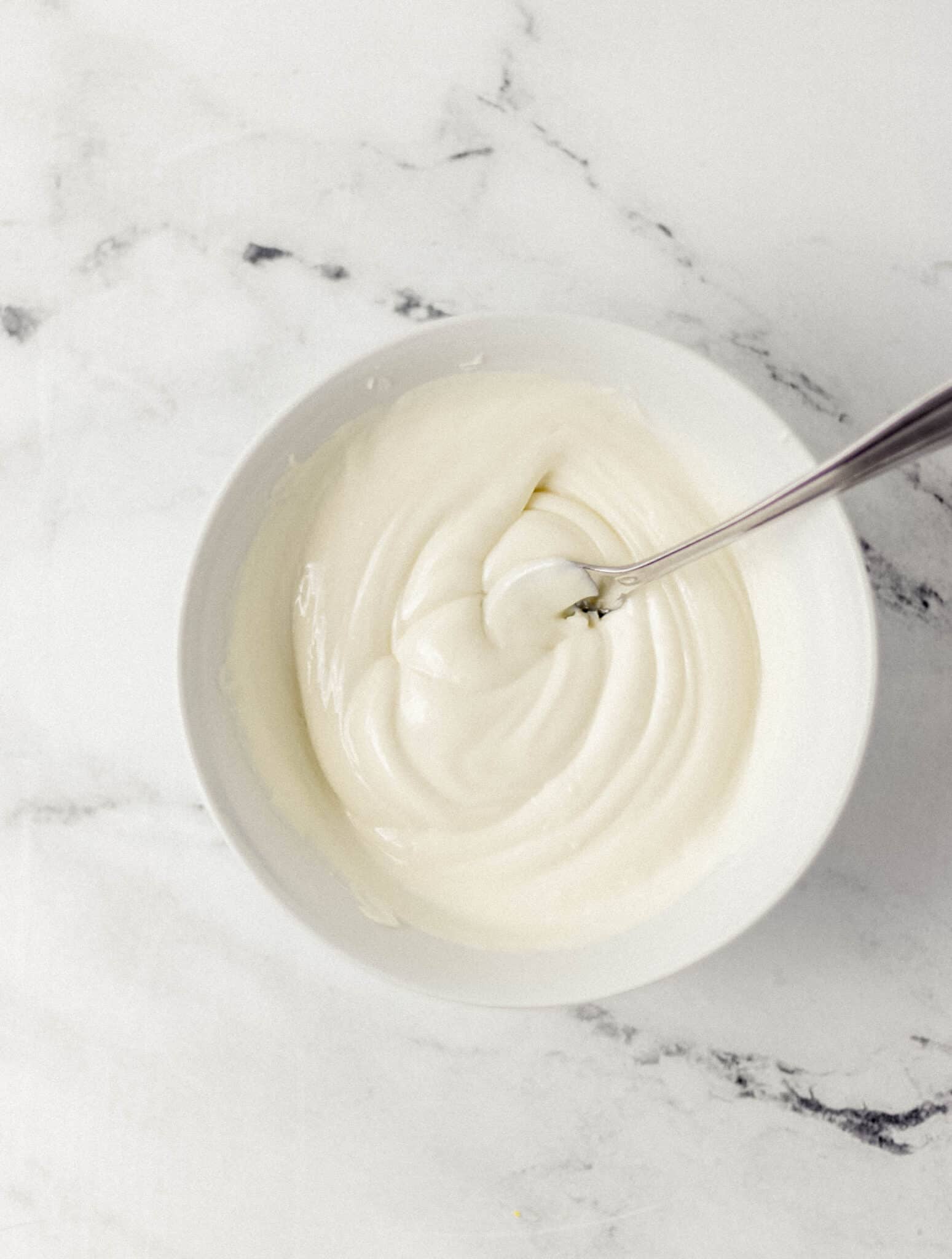 melted white chocolate in a white bowl with a fork 