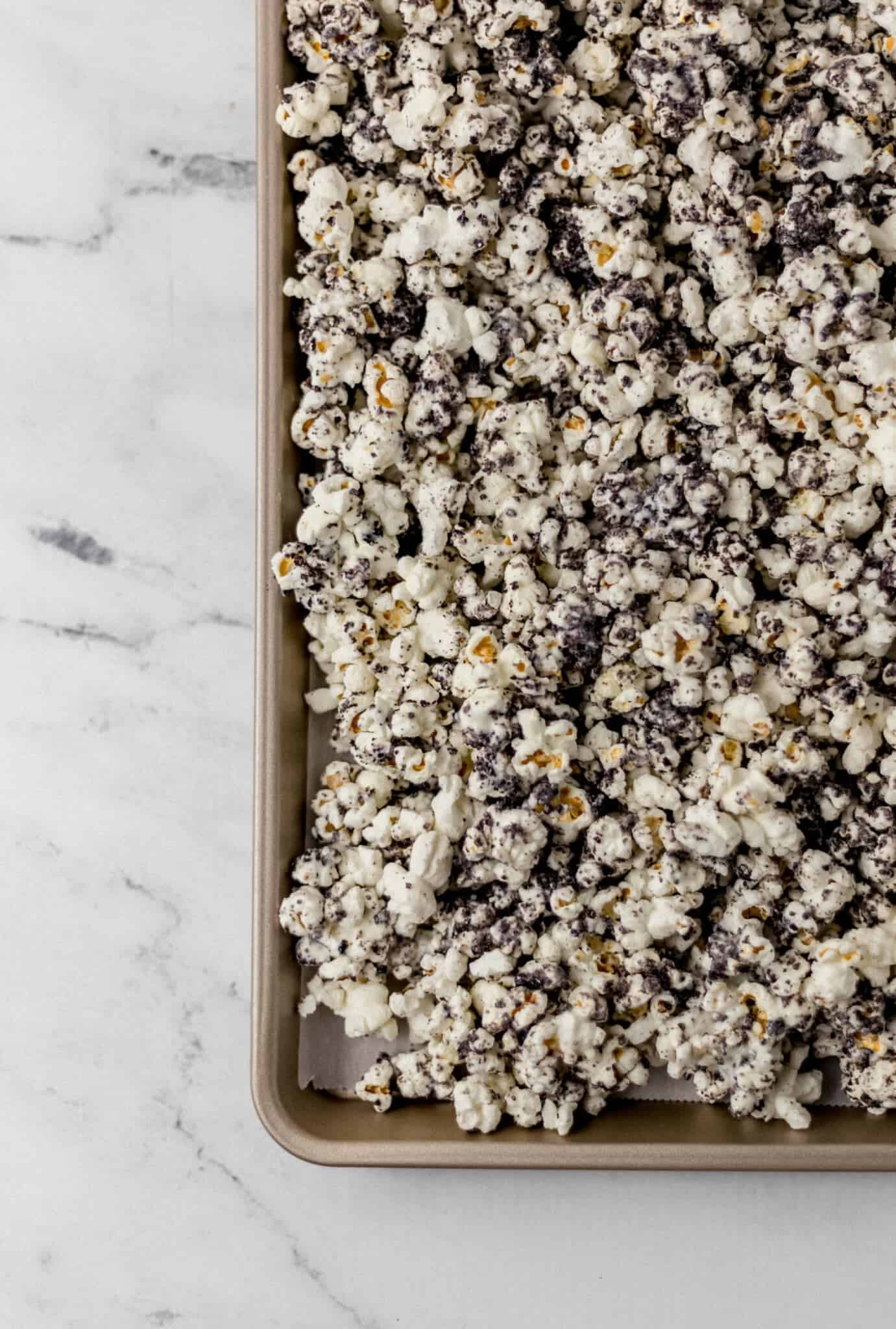 overhead view of finished cookies and cream popcorn on parchment lined baking sheet 