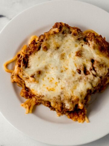 Overhead view of white plate with baked spaghetti on it.