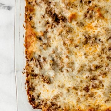 Overhead view of finished baked spaghetti in glass baking dish on marble surface.