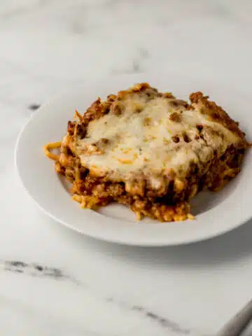 close up side view of single serving of baked spaghetti on white plate
