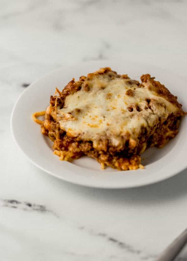 close up side view of single serving of baked spaghetti on white plate